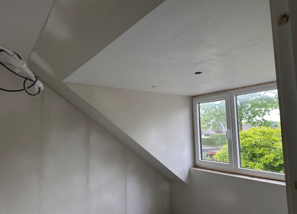 Gestucte zolderkamer met schuin plafond en een dakkapel