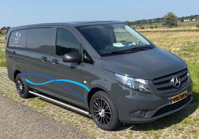 De grijze bedrijfsbus van J van Buul Stucwerken met blauwe golflijnen